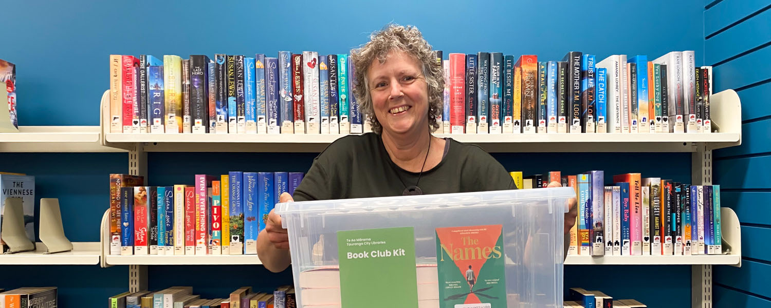Library staff member with a book club kit for group borrowing.